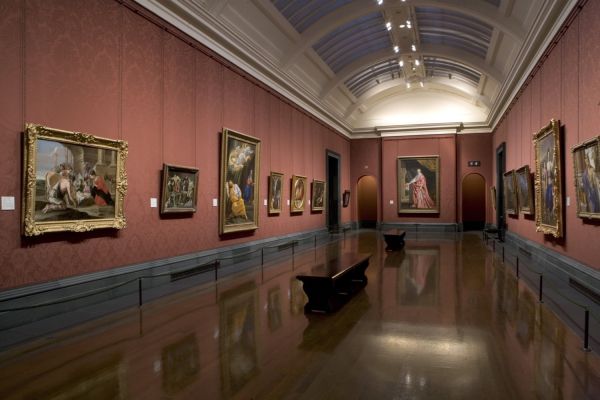 Long red-walled gallery with paintings on display at the National Gallery in London
