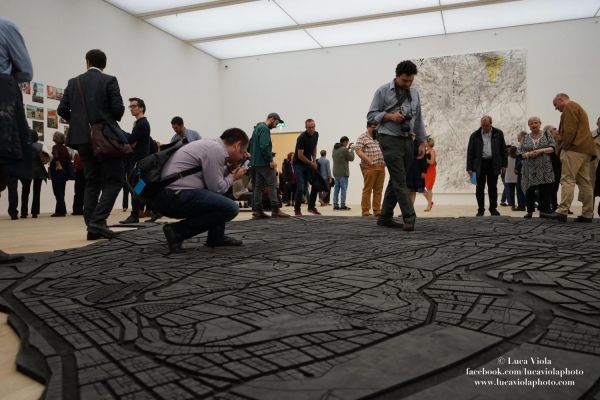 Visitors observing a large floor artwork inside a gallery at Tate Modern in London